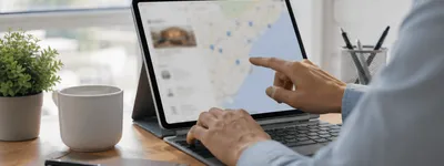 Mão apontando para um mapa com marcadores de localização na tela de um tablet, com foto de um imóvel listada ao lado do mapa