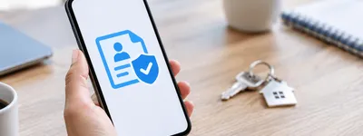 Celular exibindo um ícone abstrato de verificação sobre uma mesa, com uma chave de imóvel ao lado, sugerindo a decisão de confirmar uma reserva